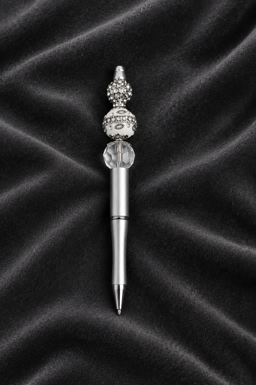 Silver and white beaded pen displayed on dark grey velvet